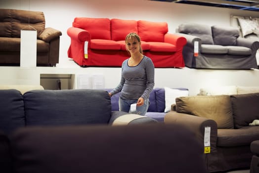 young hispanic woman shopping for furniture, sofa and home decor in store, looking at camera and smiling