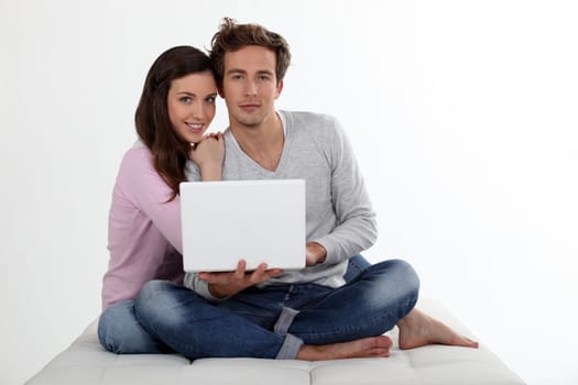 Couple using a laptop on a bed