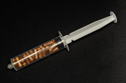 Medical Syringe Full of Pill Drugs on a Black Background