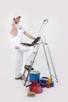 Painter posing by ladder with laptop and mobile