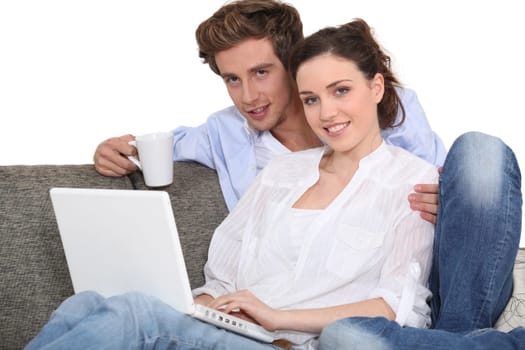 Couple using a laptop on a sofa