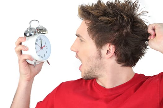Man screaming with alarm clock in hand