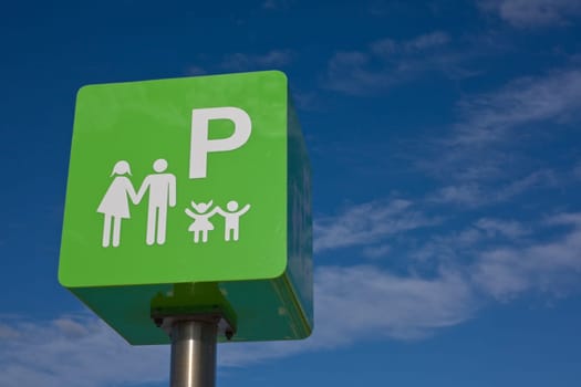 Reserved car park pole green sign for family against blue sky