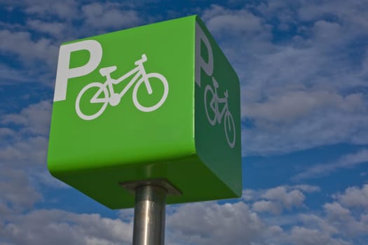 Green parking bicycle pole sign iver blue cloudy sky background