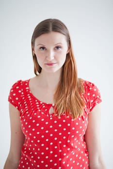 Studio portrait of thoughtful looking attractive woman wearing red spotty blouse