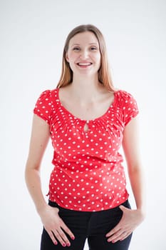 Studio portrait of happy smiling attractive woman wearing red blouse and standing with hands on hips