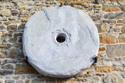 Traditional old millstone hung on a quarry stone wall