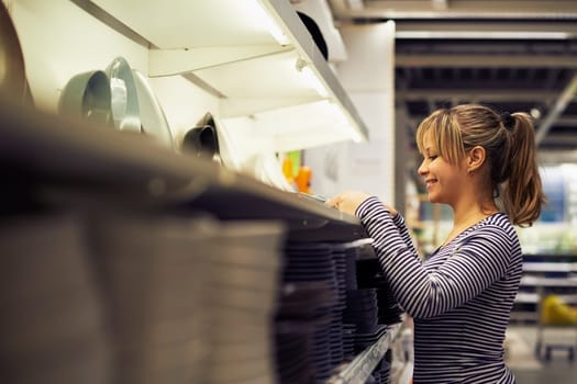 young hispanic woman shopping for furniture, glasses, dishes and home decor in store