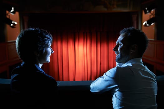 Arts and entertainment in theatre, with man and woman looking at stage with red curtains