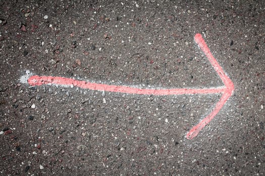 Hand drawn red  arrow on dark asphalt