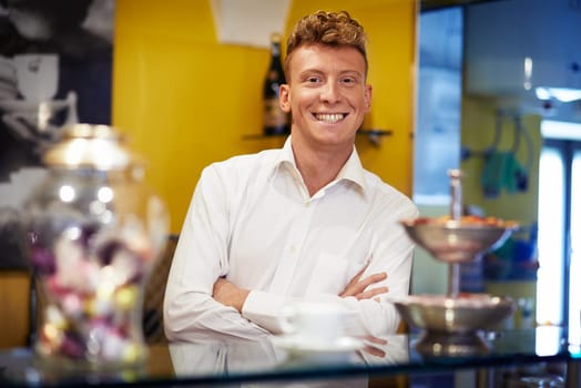 People in cafeteria, portrait of happy young man working as barman, smiling at camera behind counter