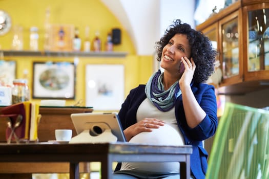 People in cafeteria, with pregnant woman drinking espresso coffee sitting at table with ipad and talking on phone