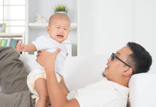 Asian family lifestyle at home. Father comforting crying baby boy.