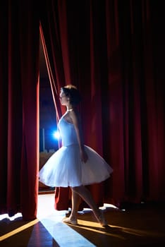 Arts and entertainment in theatre with female classic dancer in tutu, standing behind the scenes and looking at stalls