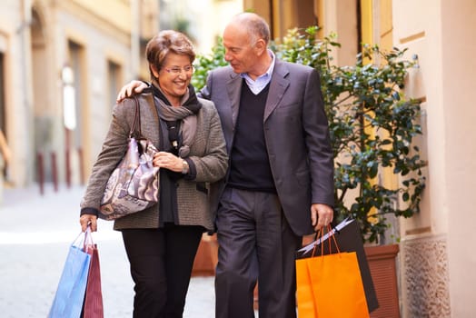 Happy people with senior man and woman shopping and walking with bags in italian city street