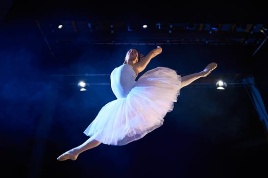 Arts and entertainment in theatre with female classic dancer in tutu, jumping high on stage during performance