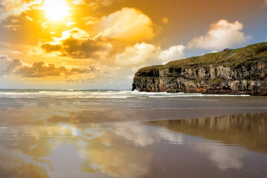 Ballybunion beach and cliffs on the Atlantic coast in Ireland with waves crashing on the cliffs at sunset