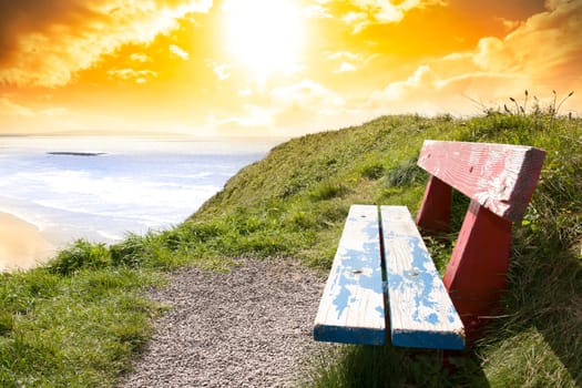 a scenic view of Ballybunion beach and Atlantic Ocean on a bright sunset evening from a bench
