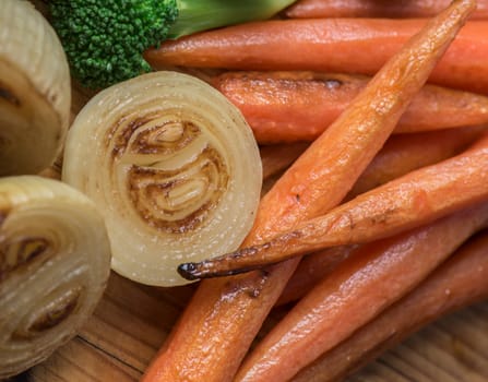 Perfectly roasted carrots and onions on a wooden platter