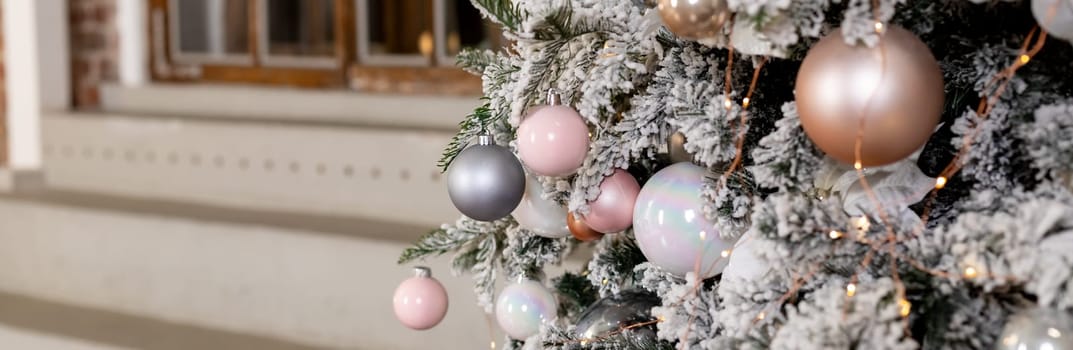 Christmas holiday composition. Christmas tree fir branches, silver balls on top border on pink pastel background with copy space.