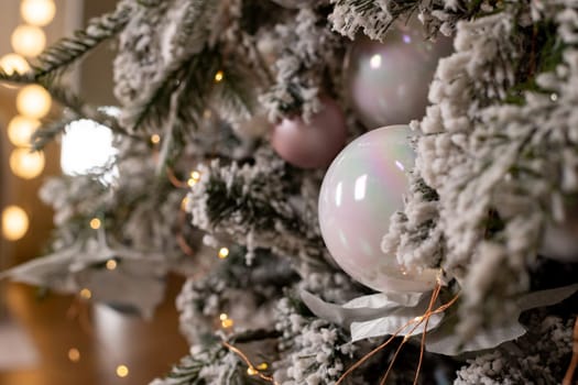 Christmas holiday composition. Christmas tree fir branches, silver balls on top border on pink pastel background with copy space.