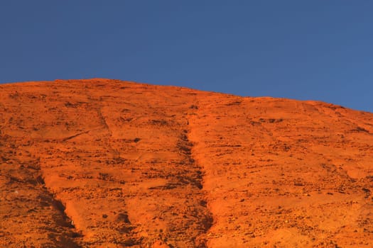 Red and orange ocher hill with blue sky in the background. 2/3 hill and 1/3 blue sky. Le Colorado Provencal de Rustrel (France)