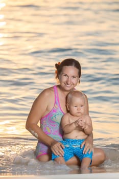 Baby and mother on the beach at sunset