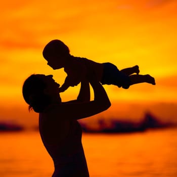 Silhouette of mother and baby at sunset