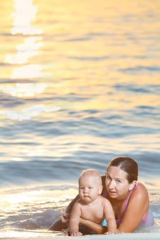 Baby and mother on the beach at sunset