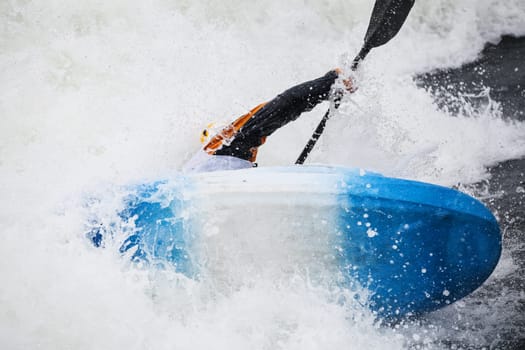 an active male kayaker rolling and surfing in rough water
