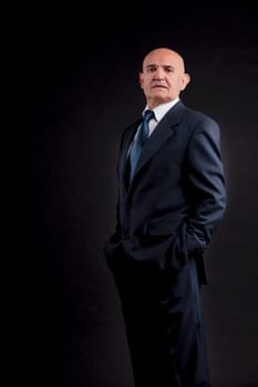 old bald self-confident businessman on a dark background