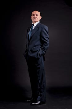 old bald self-confident businessman on a dark background