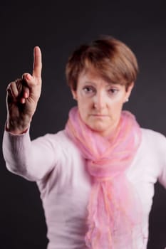 mature woman with a raised hand with index up denying or imposing