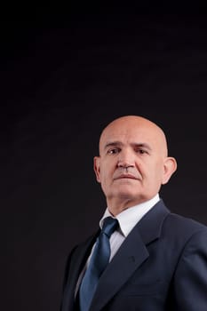 old bald self-confident businessman on a dark background