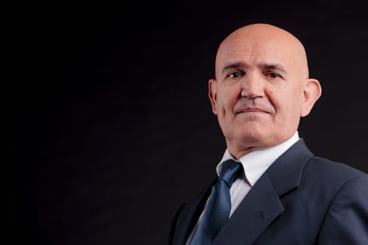 old bald self-confident businessman on a dark background
