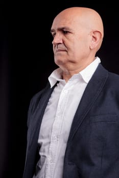 old bald self-confident businessman on a dark background