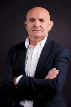 old bald self-confident businessman on a dark background