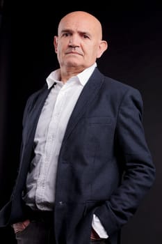 old bald self-confident businessman on a dark background