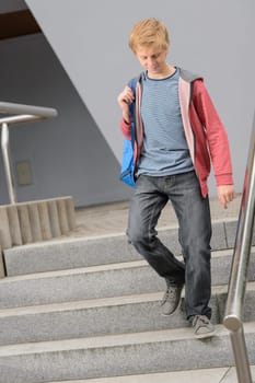 Full length of teenage student walking down university stairs