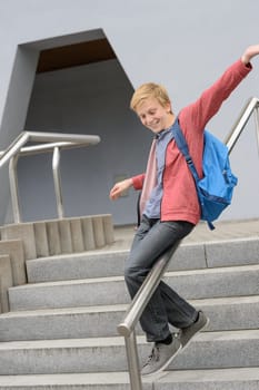 Excited teenage student sliding down handrail on school stairway