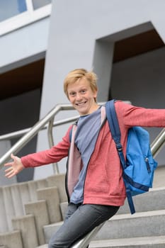 Excited teenage boy sliding down handrail on university stairway