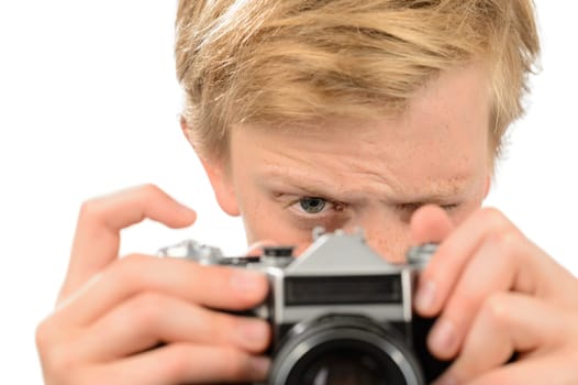 Teenage boy looking through retro camera photographing isolated on white