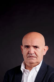 old bald self-confident businessman on a dark background