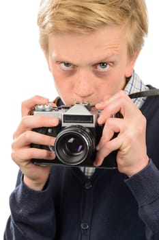 Suspicious teenage boy photographing through retro camera over white background