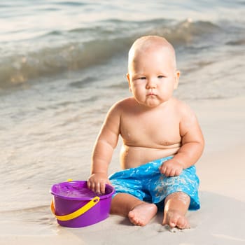 Cute baby on the tropical beach playing toys