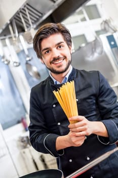 young chef prepares fresh Italian pasta spaghetti at the herd in the restaurant kitchen too