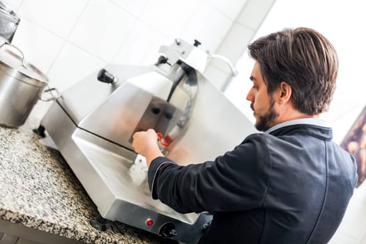 chef cuts fresh ham on the cutting machine in the restaurant kitchen