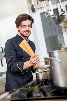 young chef prepares fresh Italian pasta spaghetti at the herd in the restaurant kitchen too