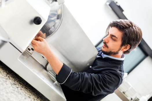 chef cuts fresh ham on the cutting machine in the restaurant kitchen