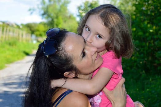 Close-up of a little girl kissing her mother